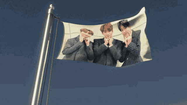 a flag with a picture of three men on it against a blue sky