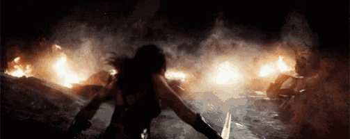 a woman is holding a sword in front of a fire at night .