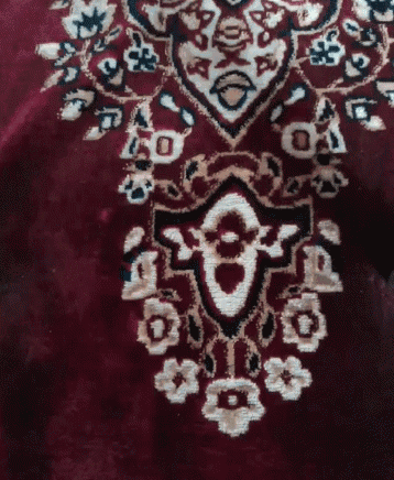 a close up of a red rug with a pattern of flowers