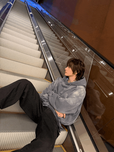 a person laying on an escalator with a hoodie on