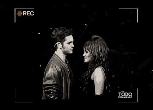 a man and a woman are looking at each other in a black and white photo taken by a camera .