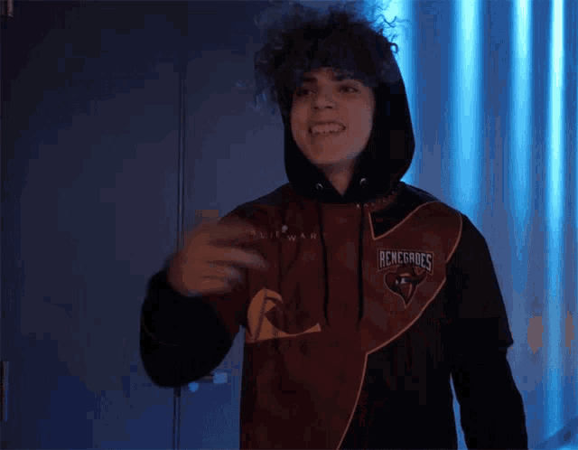 a man wearing a renegades hoodie is standing in a dark room