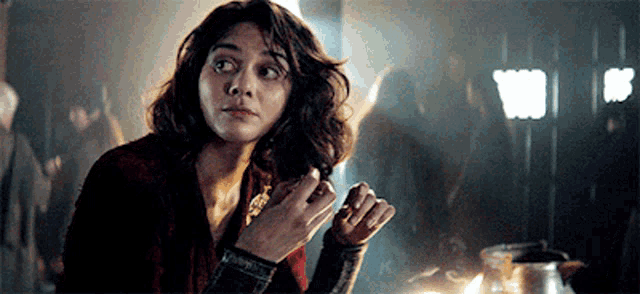 a woman with curly hair is standing in a dark room looking at something .