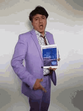 a man in a purple suit is holding a tablet with a picture on it .