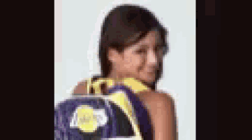 a girl is wearing a purple and yellow lakers backpack .