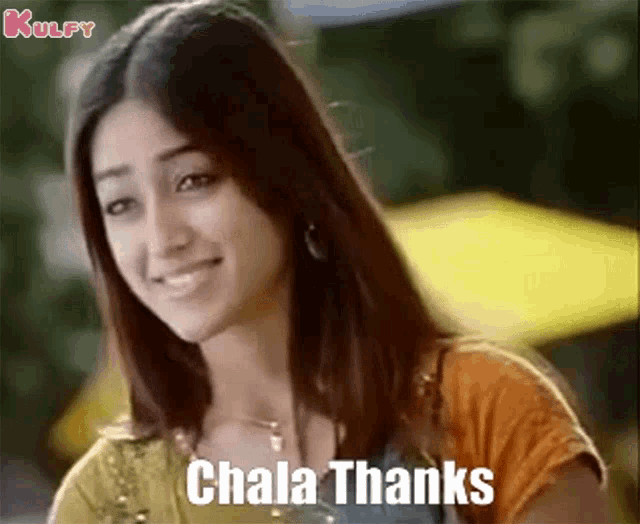 a woman is smiling and saying , ' chala thanks ' while standing in front of a yellow umbrella .