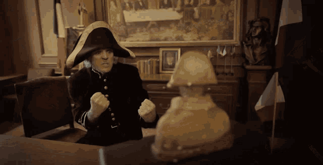 a man in a napoleon hat sitting at a desk