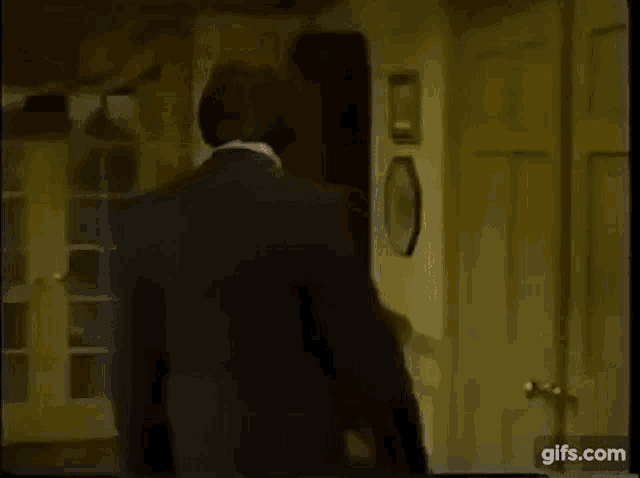 a man in a suit is opening a door in a room .