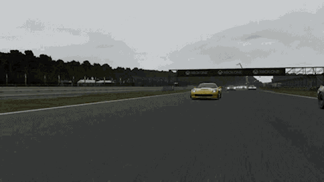 a yellow sports car is driving down a race track with xbox one banners behind it