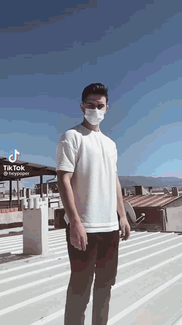 a young man wearing a mask and sunglasses is standing on a roof .