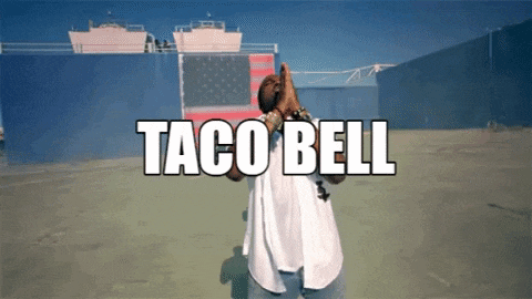 a man in a white shirt stands in front of a taco bell banner