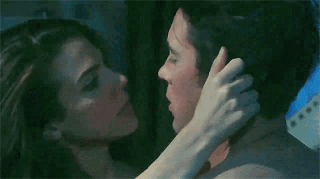 a man and a woman are kissing and the woman is holding the man 's face