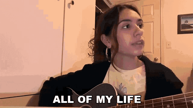 a woman playing a guitar with the words all of my life behind her