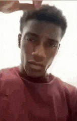 a young man wearing a red sweater is making a funny face .