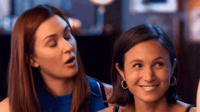 two women are sitting next to each other and one of them is wearing hoop earrings