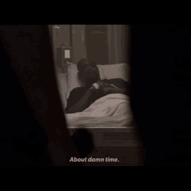 a man laying in a hospital bed with the words about damn time below him