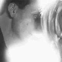 a black and white photo of a man and a woman kissing .