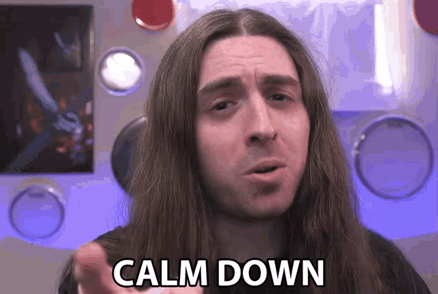a man with long hair says calm down in front of a drum set