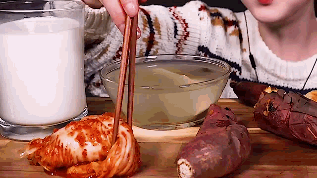 a woman is holding chopsticks over a bowl of food next to a glass of milk