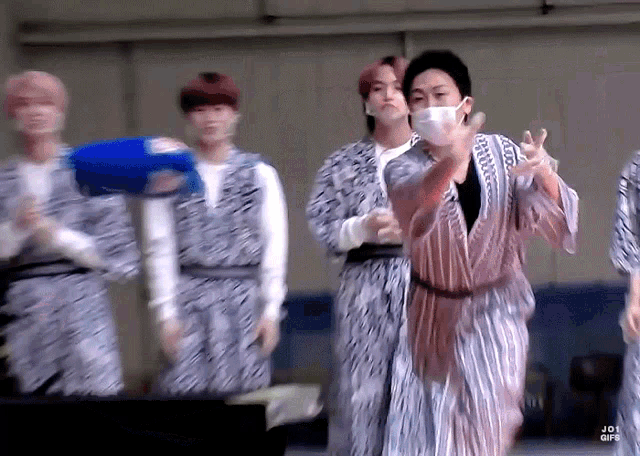 a group of young men wearing kimonos and masks are playing a game .