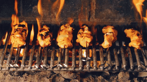 chicken skewers cooking on a grill with flames