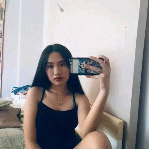 a woman is taking a selfie in a mirror with her phone .