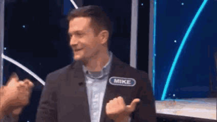 a man in a suit is standing on a stage with a name tag on his back that says mike .