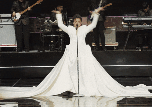 a woman in a white dress singing into a microphone
