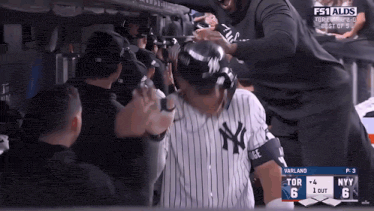 a new york yankees baseball player is being congratulated by his teammates in the dugout