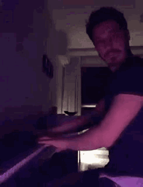 a man is playing a piano in a dark room in a dark room .