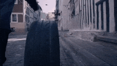 a person is pushing a tire down a sidewalk