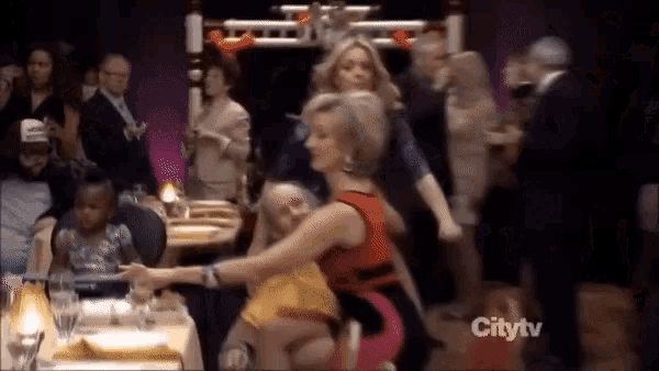 a woman in a red dress is dancing in front of a crowd at a party .