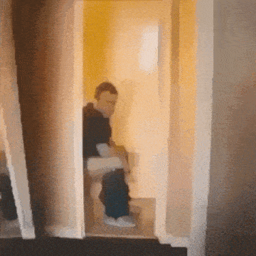 a man is sitting on a toilet in a bathroom with a door open .