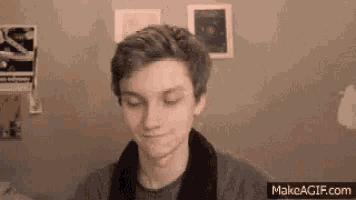 a young man is making a funny face in front of a wall with pictures on it .