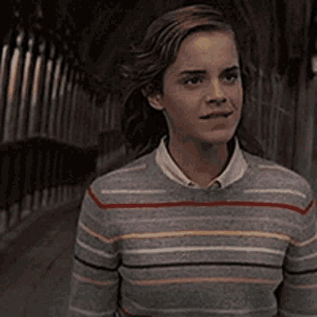 a young woman wearing a striped sweater is standing in a dark tunnel .