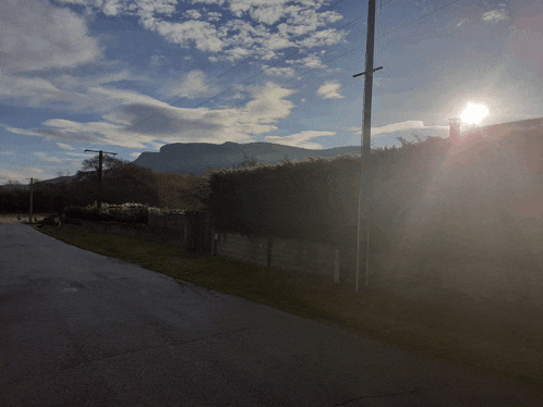 the sun is shining through the clouds over a fenced in area