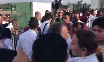 a group of people are standing in a crowd and a man is taking a picture .