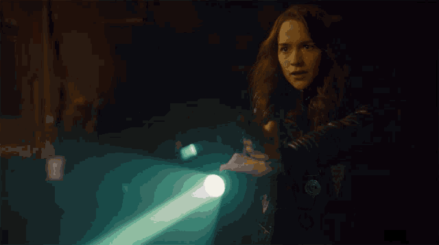 a woman is holding a flashlight in a dark room and the light is shining on her hand