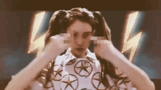 a woman with pigtails and a lightning bolt in the background is covering her eyes with her hands .