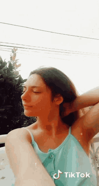 a woman in a blue tank top is taking a selfie with a tik tok watermark