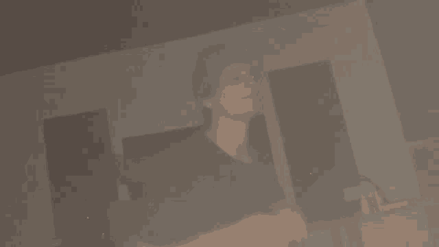a man in a black shirt is standing in a dark room smoking a cigarette