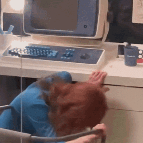 a person sitting at a desk with a computer and a blue cup that says ' oasis ' on it