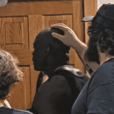 a man touches another man 's head with his hand
