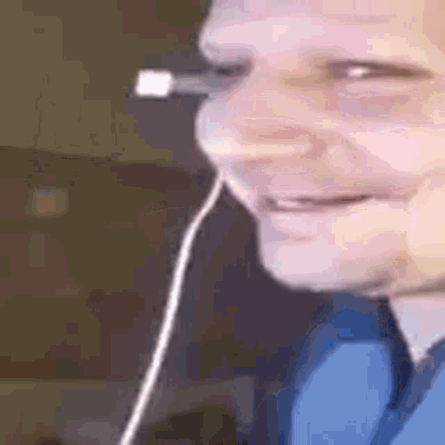 a man wearing headphones is making a funny face while looking at his phone .