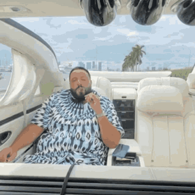 a man in a leopard print shirt is smoking a cigar in the back seat of a car