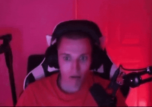 a man wearing headphones is sitting in a chair in front of a microphone in a red room .