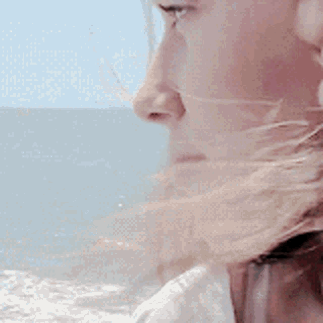 a close up of a woman looking at the ocean