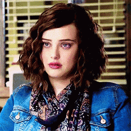 a woman wearing a denim jacket and a scarf is looking at the camera .