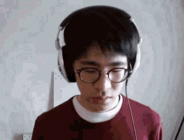a man wearing glasses and headphones is looking down .