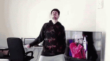 a man is dancing in a living room in front of a tv .